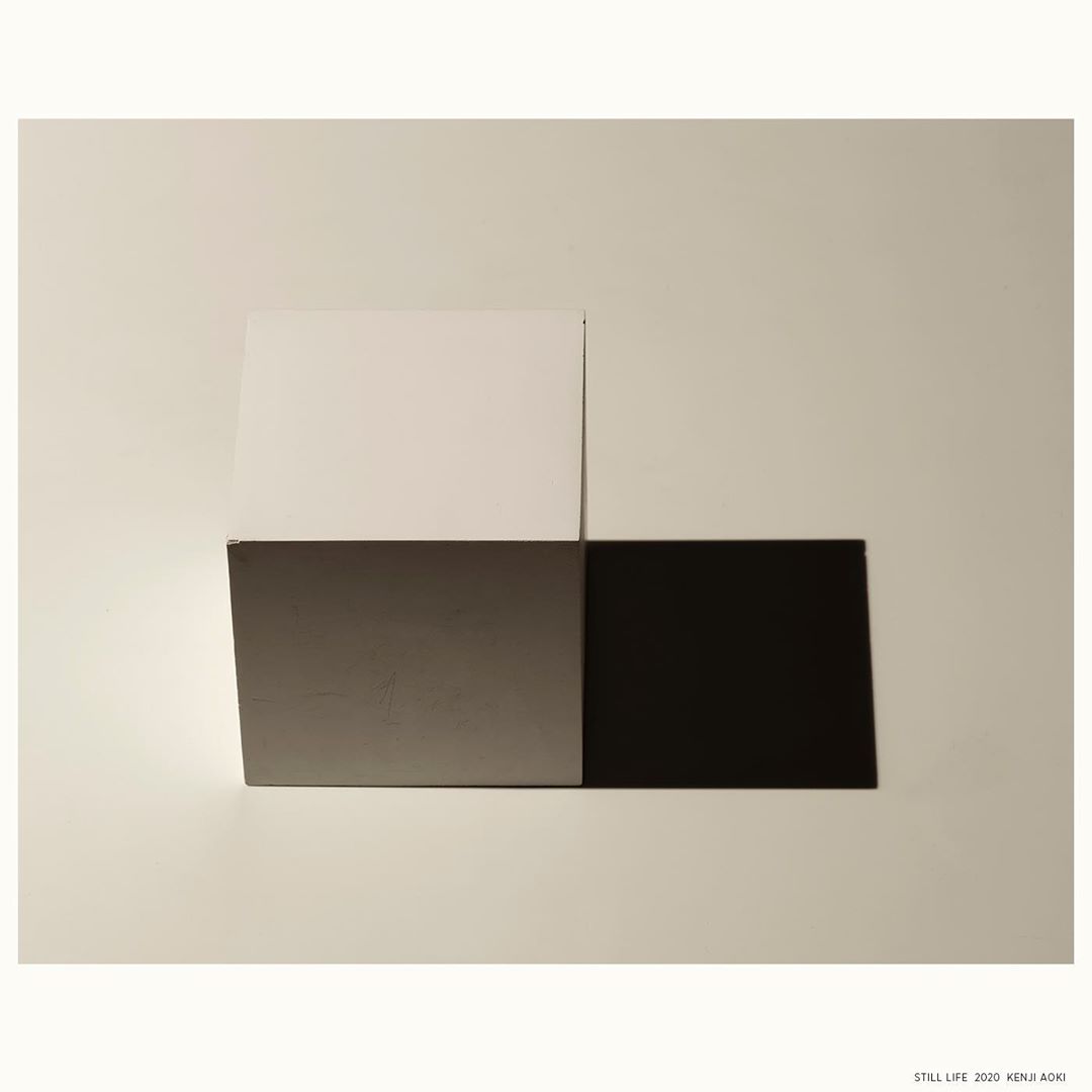 Abstract still life with geometric blocks in white, gray, and black on a neutral surface; modern photography with minimalist composition.