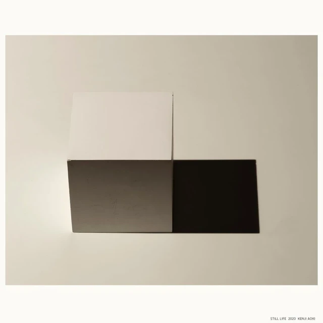 Abstract still life with geometric blocks in white, gray, and black on a neutral surface; modern photography with minimalist composition.