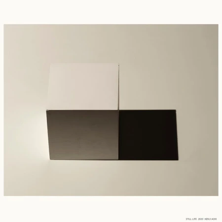 Abstract still life with geometric blocks in white, gray, and black on a neutral surface; modern photography with minimalist composition.