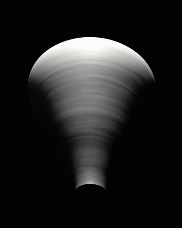 Abstract black and white photography of a swirling pattern creating a funnel shape with a rounded top against a dark background.