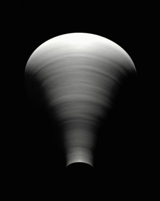 Abstract black and white photography of a swirling pattern creating a funnel shape with a rounded top against a dark background.