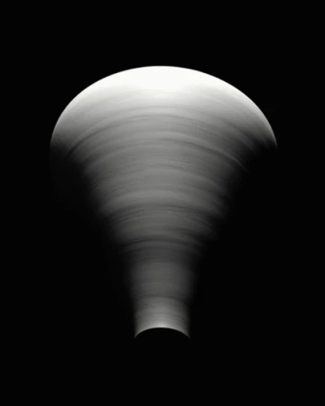 Abstract black and white photography of a swirling pattern creating a funnel shape with a rounded top against a dark background.