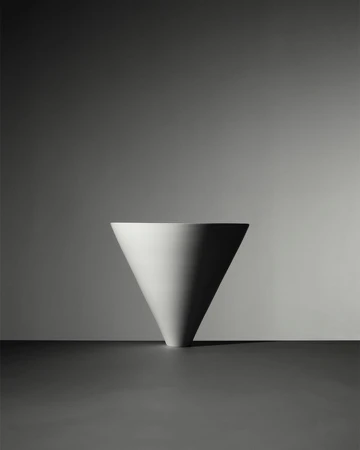 Minimalist white inverted cone ceramic vase centered on a dark surface against a graduated grey background