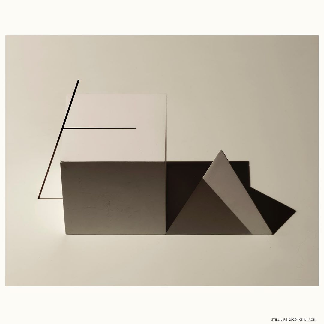 Abstract geometric art with angular shapes in white, gray, and black against a light beige background, minimalist design.