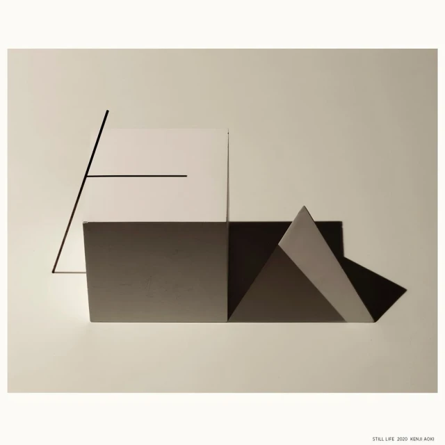 Abstract geometric art with angular shapes in white, gray, and black against a light beige background, minimalist design.