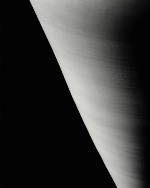 Monochromatic image of planet with striated cloud bands against a dark, stark, contrasting background. High contrast. 