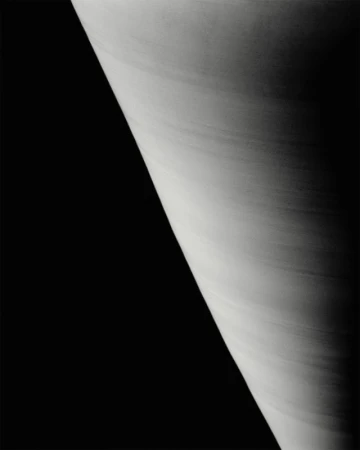 Monochromatic image of planet with striated cloud bands against a dark, stark, contrasting background. High contrast. 