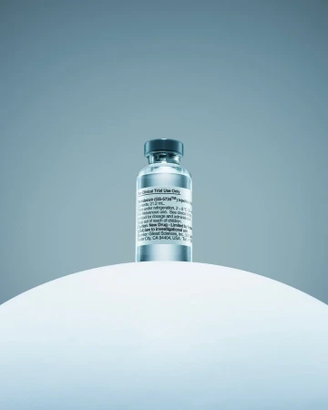 A close-up showcases a vial of Remdesivir atop a white, rounded surface against a soft, gradient blue backdrop, emphasizing its pharmaceutical nature.