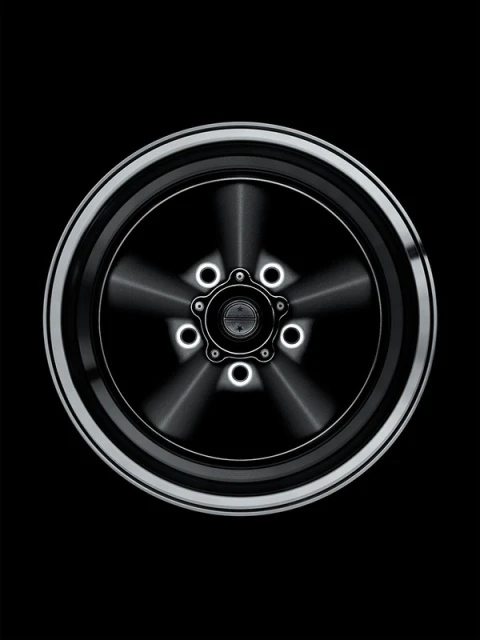 Close-up of a stylized silver and black car wheel with a five-star center design against a dark background, automotive design.