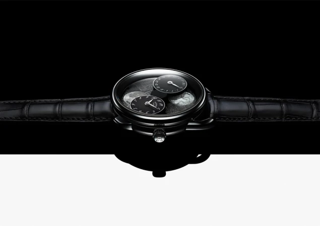 Elegant black wristwatch with a leather band, featuring a sophisticated dial with multiple sub-dials, set against a stark black and white background.