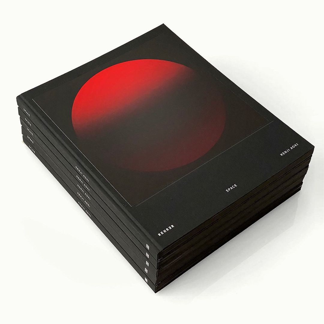 Stack of black 'SPACE' art books with red circular graphic on the cover, clean studio background.