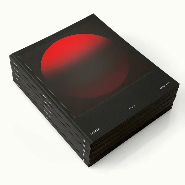 Stack of black 'SPACE' art books with red circular graphic on the cover, clean studio background.