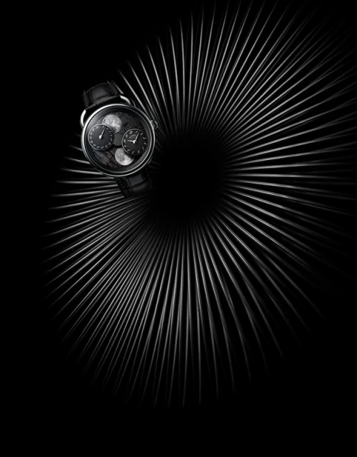 Elegant wristwatch on a black leather strap presented against an abstract radial silver line pattern on a dark backdrop creating a dramatic effect.