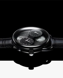 Close-up product shot of a luxury black wristwatch with subsidiary dials and leather strap on a glossy black surface.