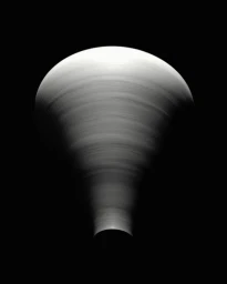 Close-up monochromatic still life of a rotating cone-shaped sculptural object against a solid black background.