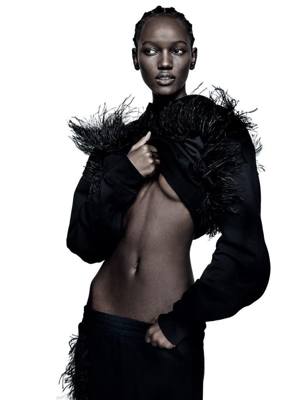 Elegant studio shot of a slender Black woman in a cropped feathered jacket and matching skirt against a pure white background.