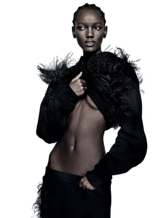 Elegant studio shot of a slender Black woman in a cropped feathered jacket and matching skirt against a pure white background.