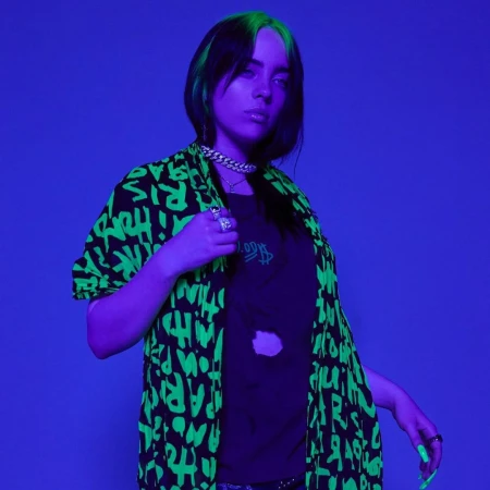 Billie Eilish wearing a black and green graphic shirt under purple studio lighting