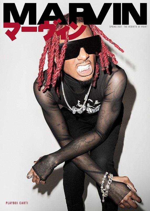 Playboi Carti cover image. Male fashion model in black translucent top with red dreads, statement sunglasses, and jewelry.