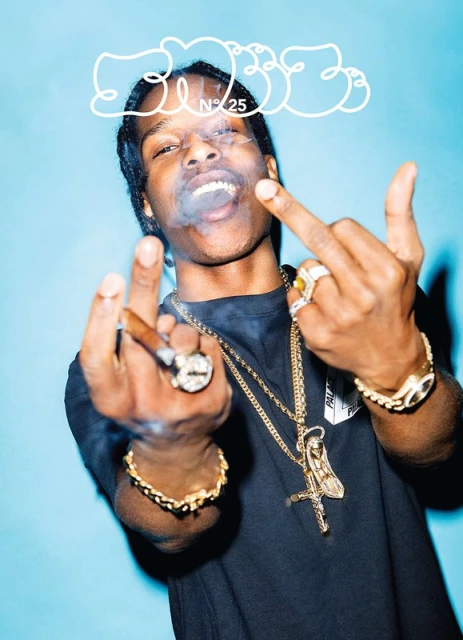 Portrait of a male model smoking a cigar, wearing jewelry and a black top, against a light blue background with cloud graphic.