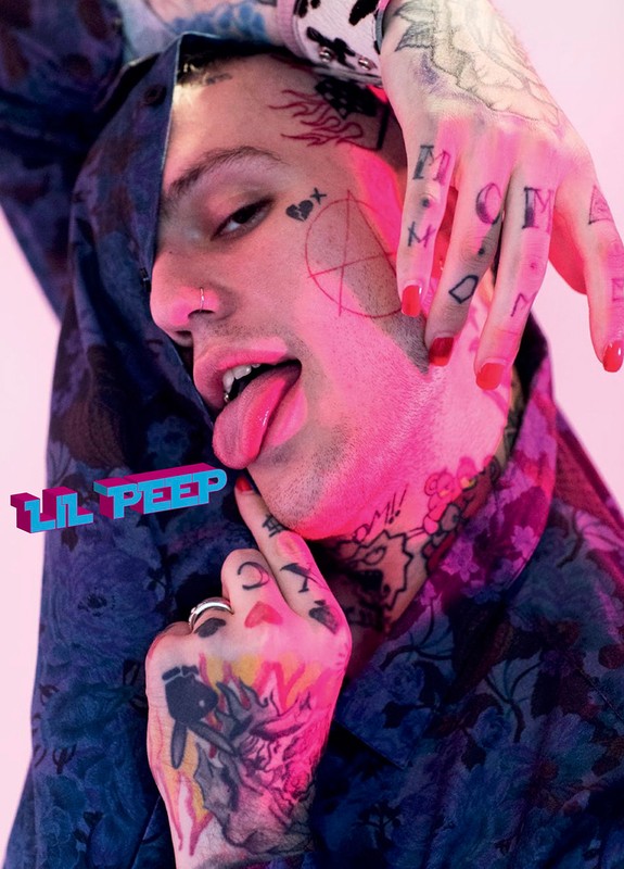 Close-up studio shot of a young adult man with facial tattoos and his tongue sticking out, with a hand on his face and the words 'Lil Peep'.