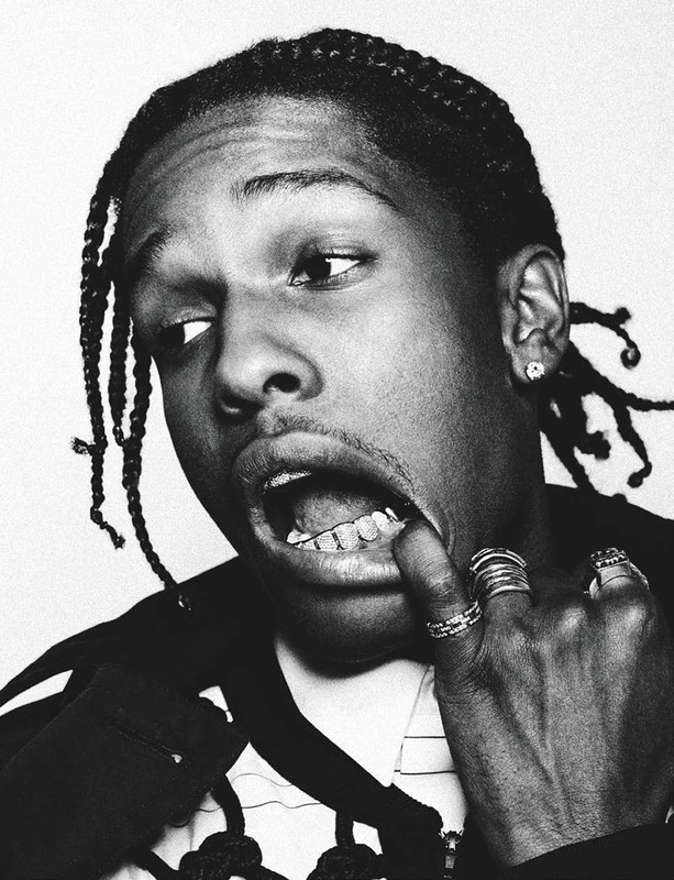 Close-up black and white portrait of a man with his mouth open, finger near his mouth, and a background of white.