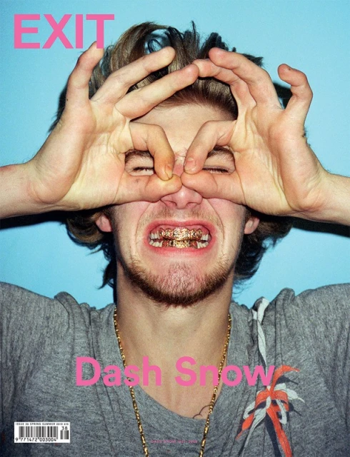 Magazine cover featuring a young adult male with styled hair, gold teeth grill, and hands forming makeshift binoculars in front of blue backdrop.
