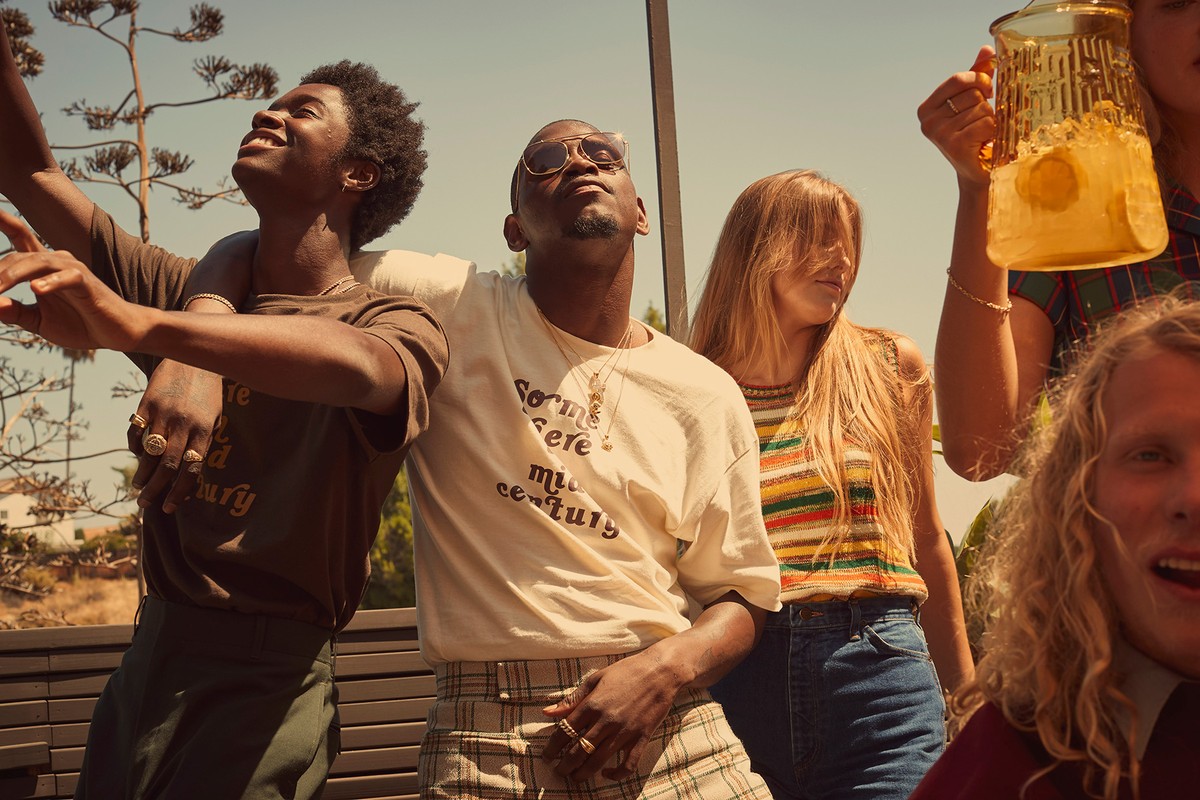 Group of diverse young adults outdoors with a drink pitcher, captured in warm, natural lighting with a shallow depth of field. Fashion and lifestyle.
