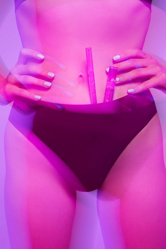 Close-up studio shot of a person holding pink makeup, emphasizing beauty and cosmetic product presentation with vibrant lighting.