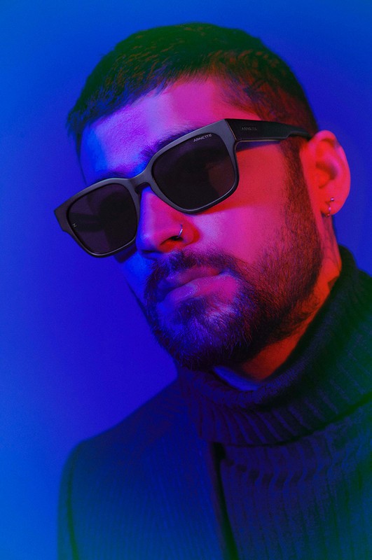 Portrait of a man wearing sunglasses against a blue and red light backdrop, showcasing contemporary fashion and portrait photography.
