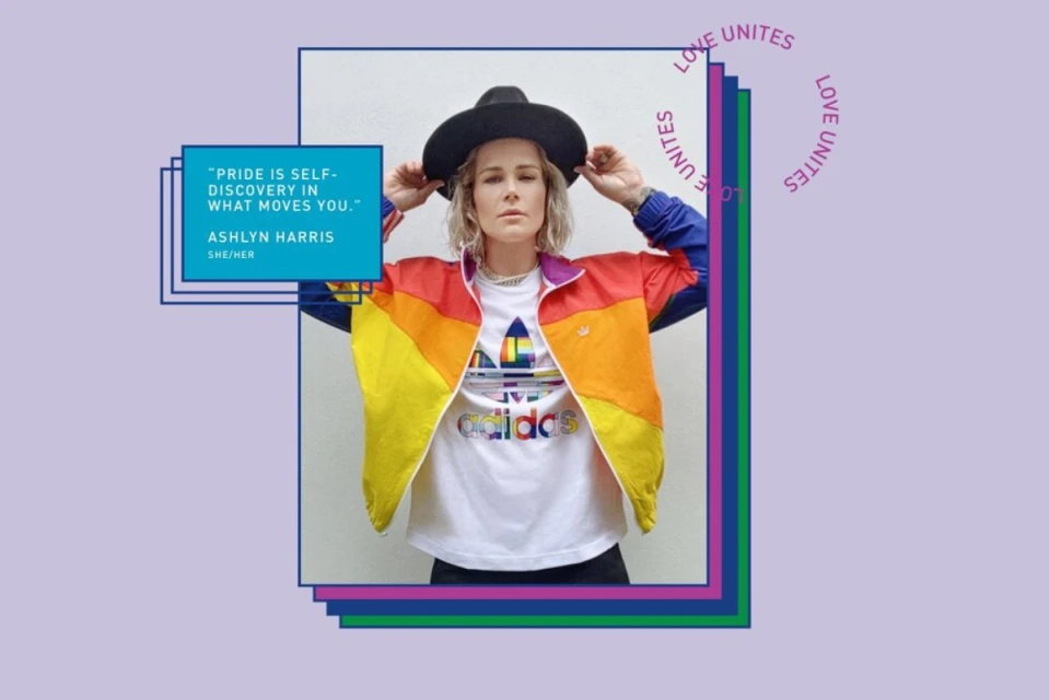 Woman in rainbow jacket and black hat poses in front of framed quote graphic promoting 'Pride is Self-Discovery in What Moves You'.