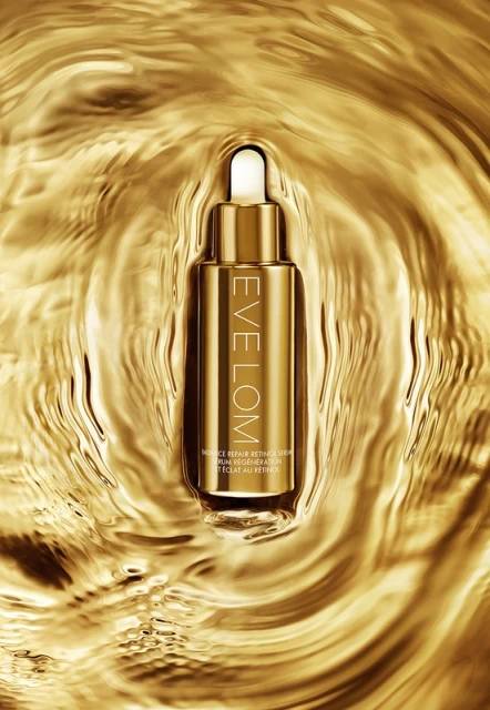 Gold bottle of Eve Lom skincare product is centered on a background of moving gold liquid, creating a luxurious beauty product shot.