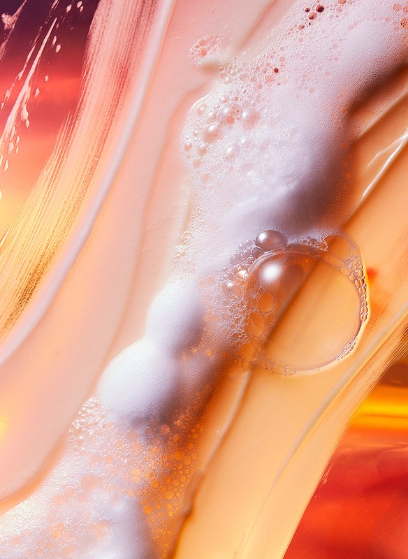 Macro shot of an orange and white liquid with bubbles and streaks, evoking a sense of movement and abstract beauty.