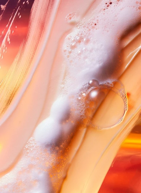 Macro shot of an orange and white liquid with bubbles and streaks, evoking a sense of movement and abstract beauty.
