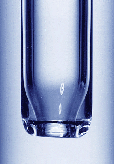 Close-up of a clear glass test tube filled with a blue liquid. The curved bottom of the tube is visible in the light.