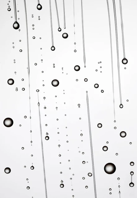 Macro photograph of clear liquid lines and suspended bubbles against a bright white backdrop, creating a minimalist aesthetic.
