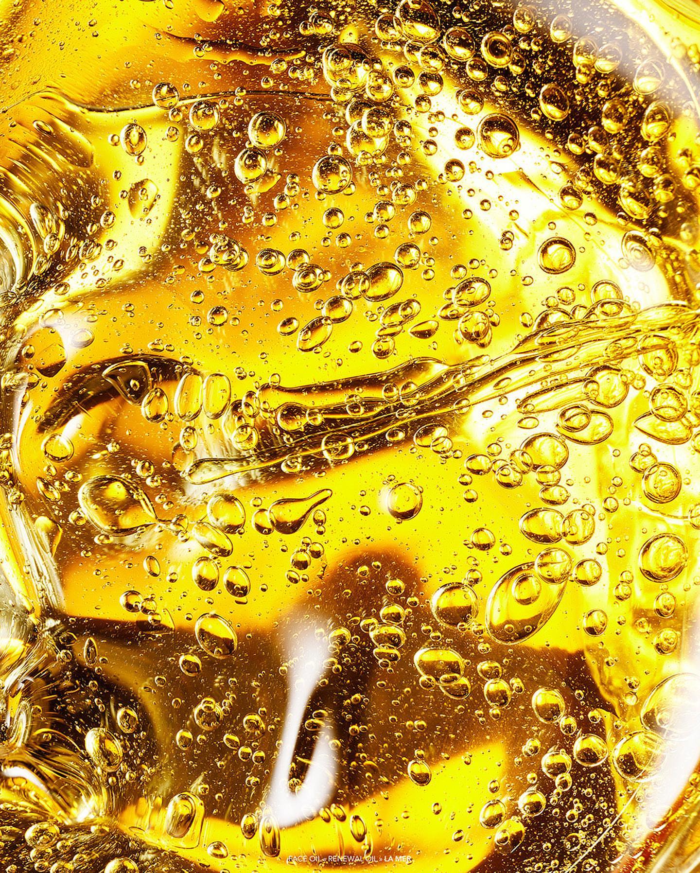 Close-up shot of a translucent, golden-yellow liquid with suspended bubbles, showcasing its texture and light refraction for various applications.
