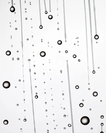 Abstract image of water droplets and thin streams against a bright white background, creating a visually interesting, minimalist composition.
