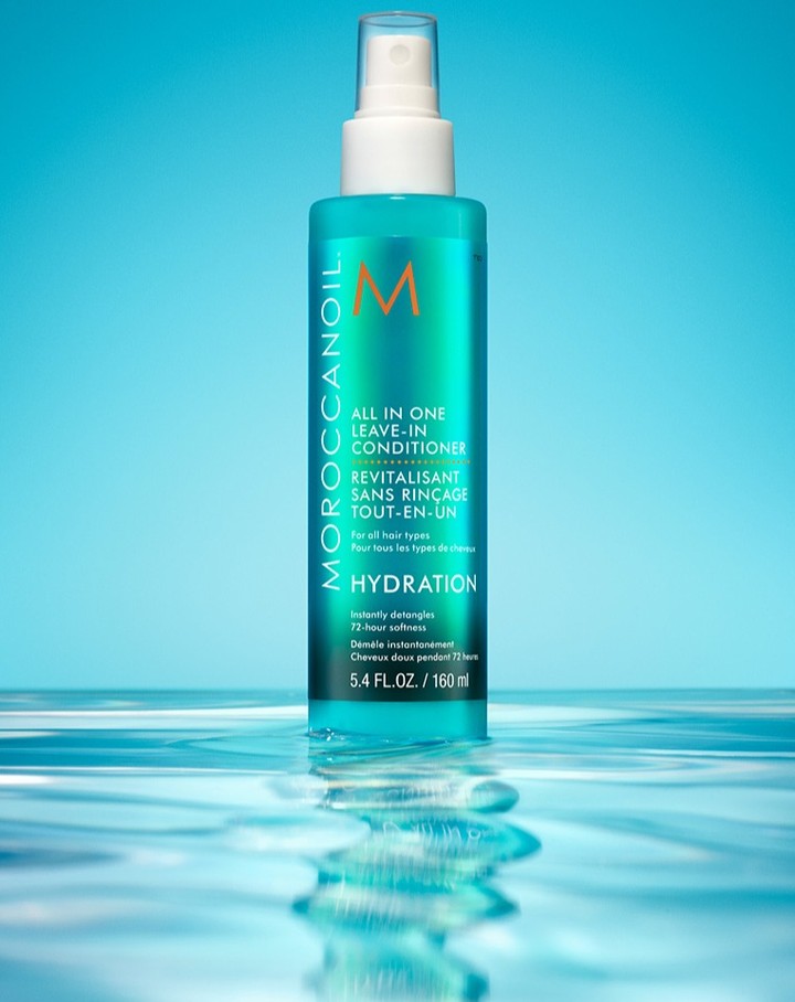 Moroccanoil All in One Leave-In Conditioner product shot against a blue background with a water surface reflecting the bottle's image.