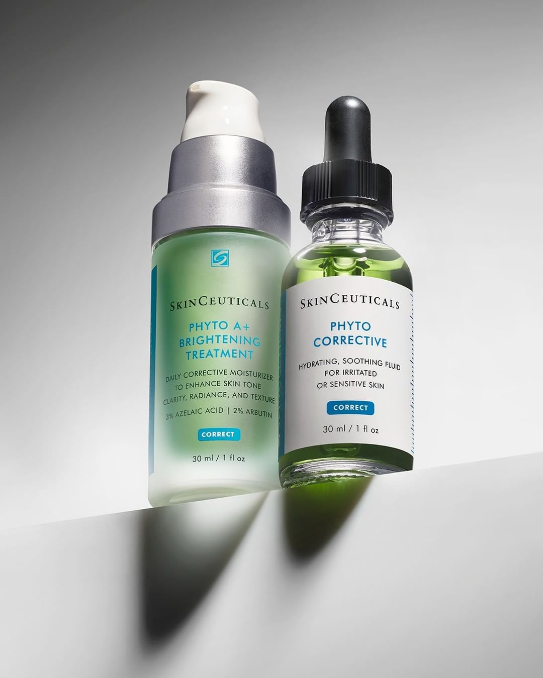 Two bottles of SkinCeuticals Phyto Corrective serum and treatment stand on a white surface against a gradient gray background.