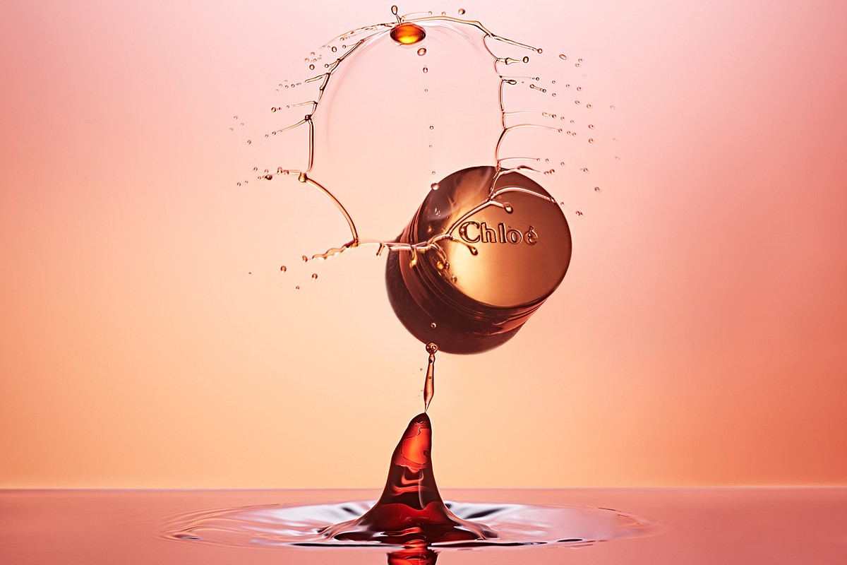 Chloe perfume bottle mid-splash creating crown effect in studio with water droplet, elegant, rose gold tones, Beauty industry product shot.