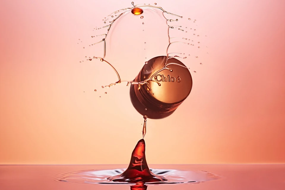 Chloe perfume bottle mid-splash creating crown effect in studio with water droplet, elegant, rose gold tones, Beauty industry product shot.