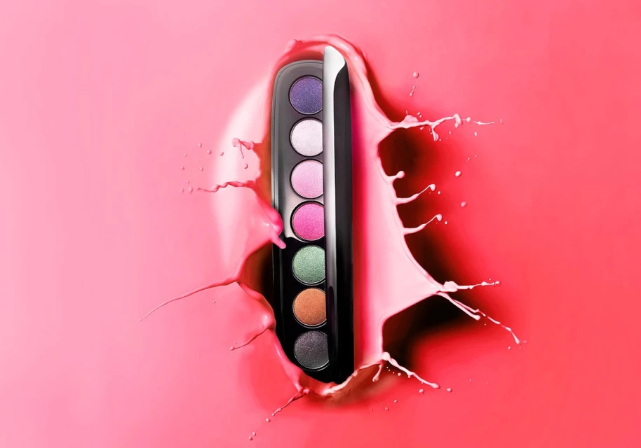 Eye shadow palette against a pink background with a splash of pink liquid surrounding it, for beauty and makeup product photography.