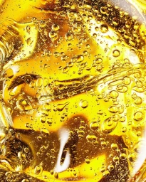 Close-up abstract view of golden amber oil with suspended bubbles and fluid liquid textures.