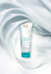 Moroccanoil color depositing mask tube centered amidst flowing light grey silky fabric drapes