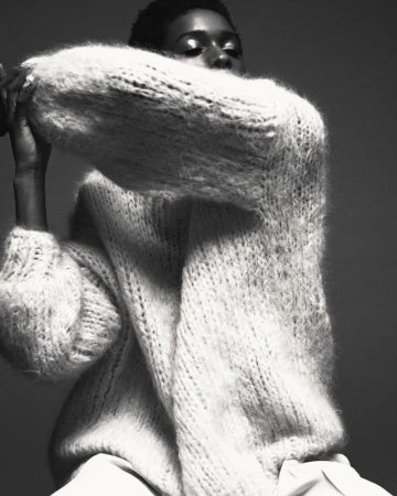 Black and white portrait of a woman in a heavy knitted sweater with voluminous sleeves by Kevin Obrien