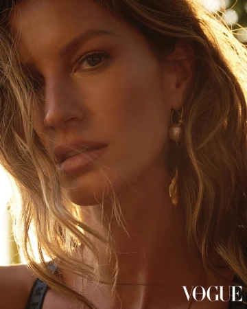 Close-up portrait of a woman with long wavy hair and gold earrings lit by warm sunlight.
