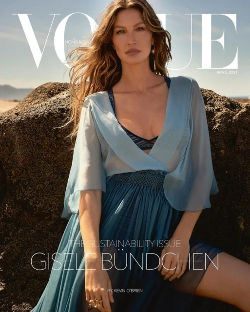 Vogue Hong Kong cover featuring Gisele Bundchen in a flowing blue dress, set against a textured rock formation and sandy beach.