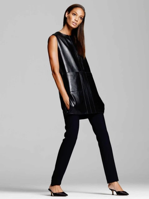 A sleek, dark-haired woman poses in a sleeveless black leather dress and black pants, completed with black kitten heel shoes.