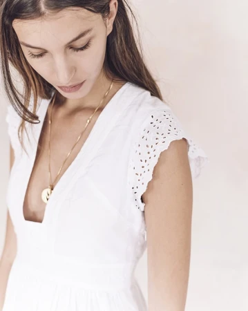 Close-up portrait of a woman wearing a white eyelet dress and gold pendant necklace, shot by Kevin Obrien